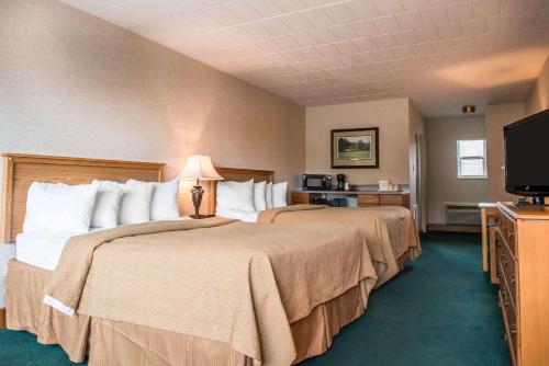 a hotel room with two beds and a flat screen tv at Quality Inn Pittsburgh Airport in Oakdale