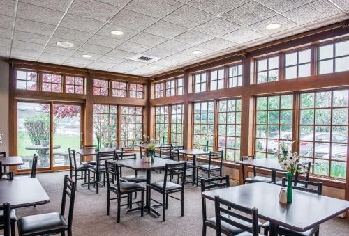 a dining room with tables and chairs and windows at Quality Inn Pittsburgh Airport in Oakdale