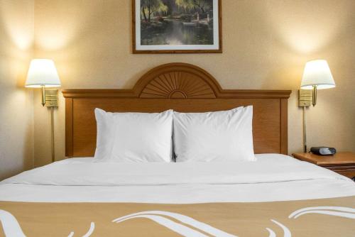 a bed with white sheets and pillows in a hotel room at Quality Inn Meadville in Meadville