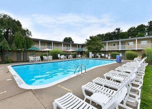 una piscina con tumbonas blancas junto a un hotel en Econo Lodge Inn & Suites Shamokin Dam - Selinsgrove, en Shamokin Dam