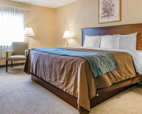 a bedroom with a large bed and a chair at Rodeway Inn Mercer in Mercer