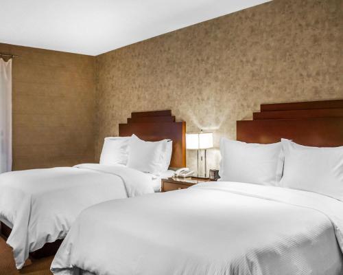 two beds in a hotel room with white sheets at The Woodlands Inn in Wilkes-Barre