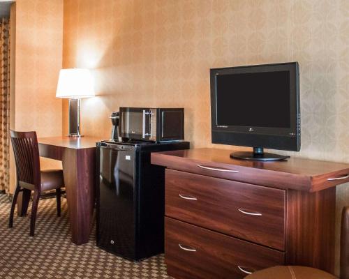 a hotel room with a television on a dresser with a desk at The Woodlands Inn in Wilkes-Barre