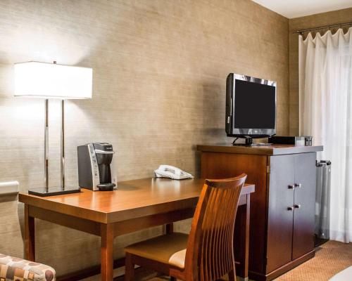 a hotel room with a desk with a tv and a telephone at The Woodlands Inn in Wilkes-Barre