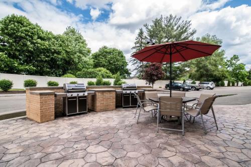 a patio with an outdoor kitchen and an umbrella at Comfort Inn & Suites Sayre in Sayre