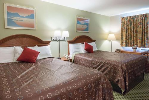 a hotel room with two beds with red pillows at Rodeway Inn Milford - I-84 in Milford