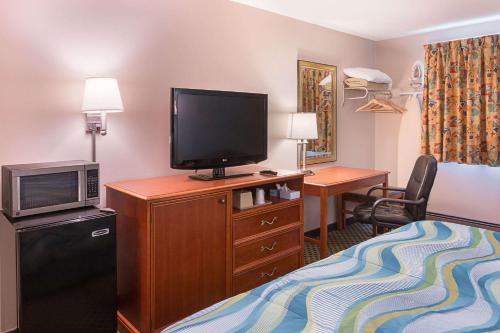 a hotel room with a television and a bed at Rodeway Inn Milford - I-84 in Milford