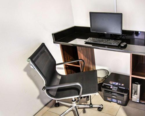 a black desk with a computer monitor and a chair at Sleep Inn near Outlets in Myrtle Beach