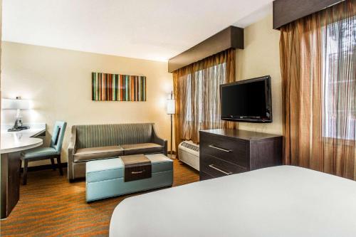 a hotel room with a bed a couch and a television at MainStay Suites Greenville Airport in Greer