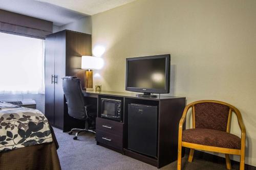 a hotel room with a bed and a television on a desk at Sleep Inn Airport in Columbia