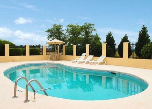 een zwembad met twee stoelen en een parasol bij Quality Inn Mullins - Marion in Country Club Estates