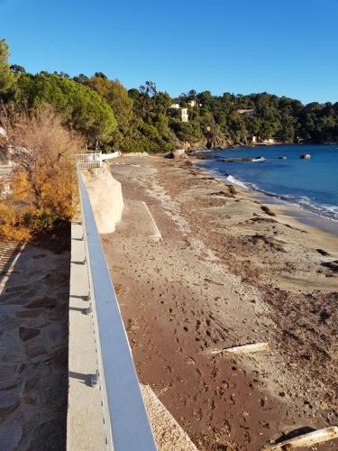 a view of a beach with a fence and the water at Les Restanques du Sud in Le Lavandou