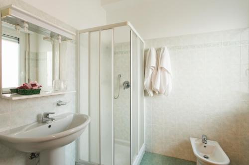 La salle de bains blanche est pourvue d'un lavabo et d'une douche. dans l'établissement Hotel Ristorante Paladini, à Carisio