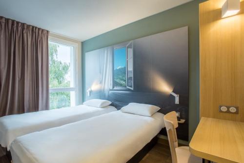 a hotel room with two beds and a window at B&B HOTEL ANNEMASSE Saint-Cergues in Saint-Cergues
