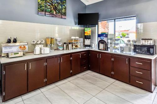 a kitchen with brown cabinets and a counter top at Rodeway Inn North Charleston - Ashley Phosphate in Charleston