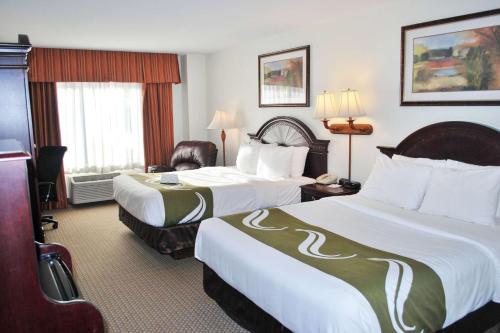 Quality Inn & Suites Airport North في شلالات سيوكس: غرفة فندقية بسريرين وكرسي