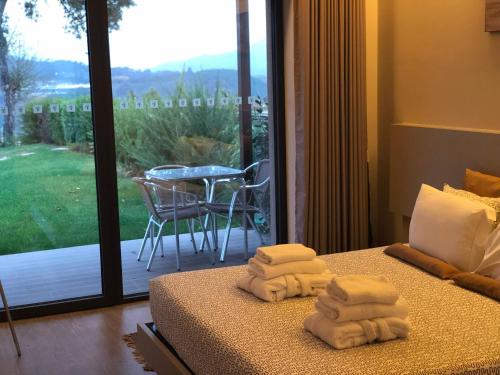 a room with two towels on a bed with a balcony at Bosque da Harmonia in Arco de Baúlhe