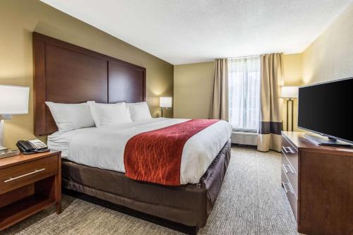 a hotel room with a bed and a flat screen tv at Comfort Inn & Suites Greenwood near University in Greenwood
