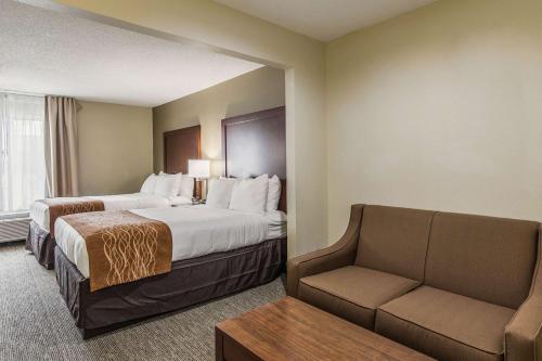 a hotel room with two beds and a couch at Comfort Inn & Suites Greenwood near University in Greenwood