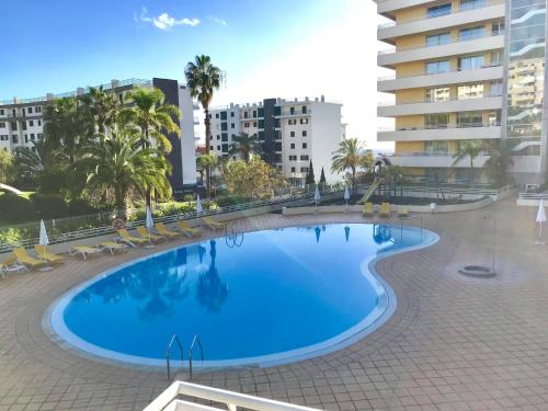 a swimming pool with chairs and a building at Enzo Apartament in Funchal