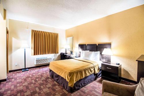 a hotel room with a bed and a desk and chair at Econo Lodge Watertown in Watertown