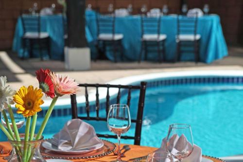 a table with glasses of wine and flowers next to a pool at Comfort Inn Real San Miguel in San Miguel
