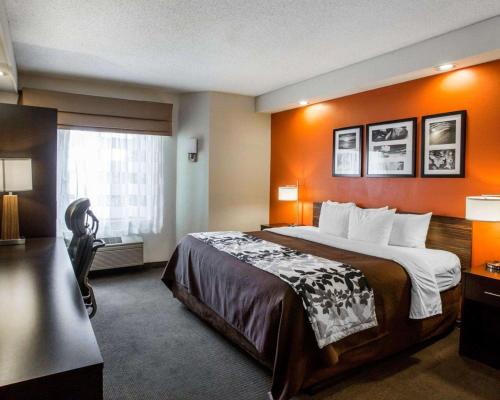 a hotel room with a large bed with an orange wall at Sleep Inn Nashville - Brentwood - Cool Springs in Brentwood