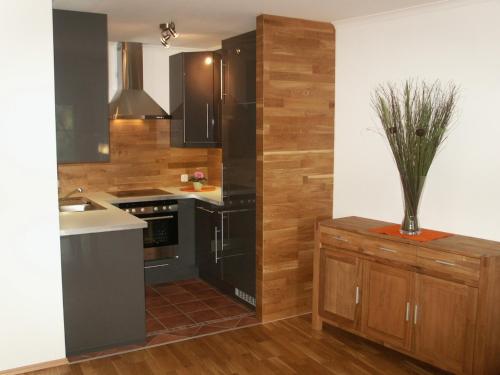 una cocina con electrodomésticos negros y armarios de madera en Salzingerhof, en Kirchdorf am Inn