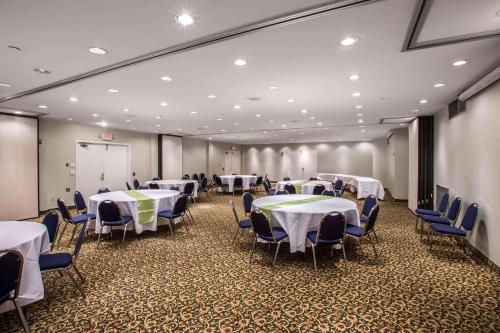 een conferentieruimte met witte tafels en stoelen en een scherm bij Greeneville Inn And Suites in Greeneville