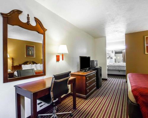 a hotel room with a desk and a bed and a mirror at Econo Lodge in Dyersburg