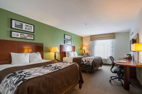 a hotel room with two beds and a desk at Sleep Inn & Suites in Manchester