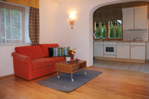 salon z czerwoną kanapą i stołem w obiekcie Appartementhaus Mentil w mieście Flattach