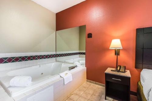 Quality Inn & Suites La Vergne في لا فيرجني: حمام مع حوض استحمام وسرير