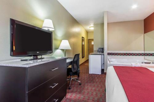 a hotel room with a bed and a flat screen tv at Quality Inn & Suites in La Vergne