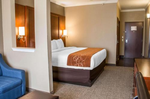 a hotel room with a bed and a blue chair at Comfort Suites New Braunfels - San Antonio Area in New Braunfels