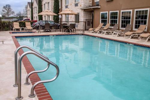 a large blue swimming pool with chairs and tables at Comfort Suites New Braunfels in New Braunfels