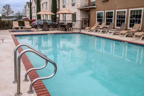 a large blue swimming pool with chairs and tables at Comfort Suites New Braunfels - San Antonio Area in New Braunfels
