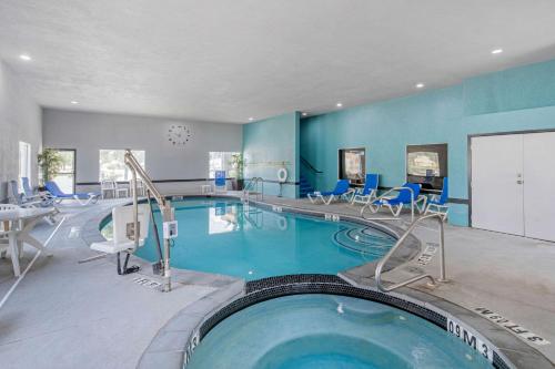 a large swimming pool in a hotel room with blue walls at Clarion Inn & Suites DFW North in Irving