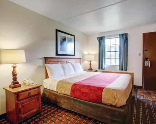 a hotel room with a bed and a table with a phone at Rodeway Inn New Braunfels - San Antonio Area in New Braunfels