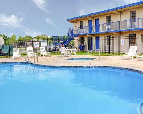 a pool with chairs and a table and a building at Rodeway Inn New Braunfels - San Antonio Area in New Braunfels