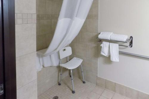 a shower with a white chair in a bathroom at Quality Inn DFW Airport North in Irving