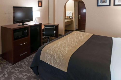 a hotel room with a bed and a flat screen tv at Comfort Inn North Conroe in Conroe