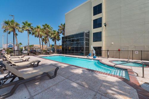 a swimming pool with lounge chairs next to a building at Comfort Suites Beachside in South Padre Island