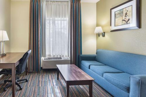 a living room with a couch and a desk in a hotel room at Quality Suites in Temple