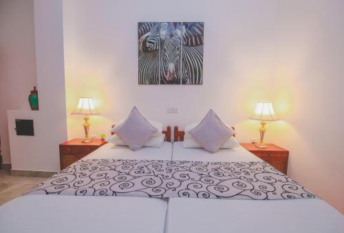 a bedroom with a bed with two lamps and a painting at Villa Paradise in Hikkaduwa