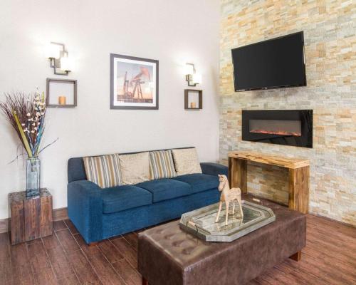 a living room with a blue couch and a fireplace at Comfort Suites Odessa near University in Odessa