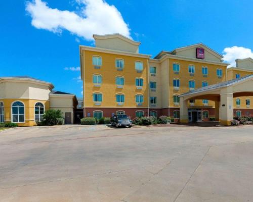 a large yellow building with a car parked in a parking lot at Comfort Suites University in Abilene