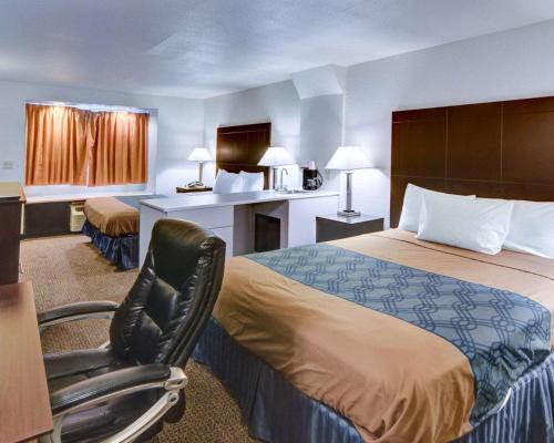 ein Hotelzimmer mit einem Bett, einem Schreibtisch und einem Stuhl in der Unterkunft Rodeway Inn & Suites Lewisville I-35 in Lewisville