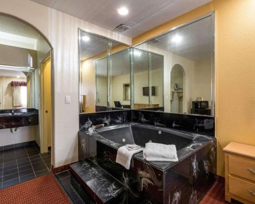 a large bathroom with a tub with a mirror at Scottish Inn & Suites IAH West in Westfield