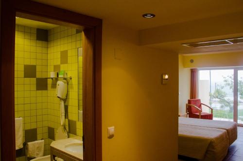 a room with a bathroom with a bed and a tub at INATEL Oeiras in Oeiras